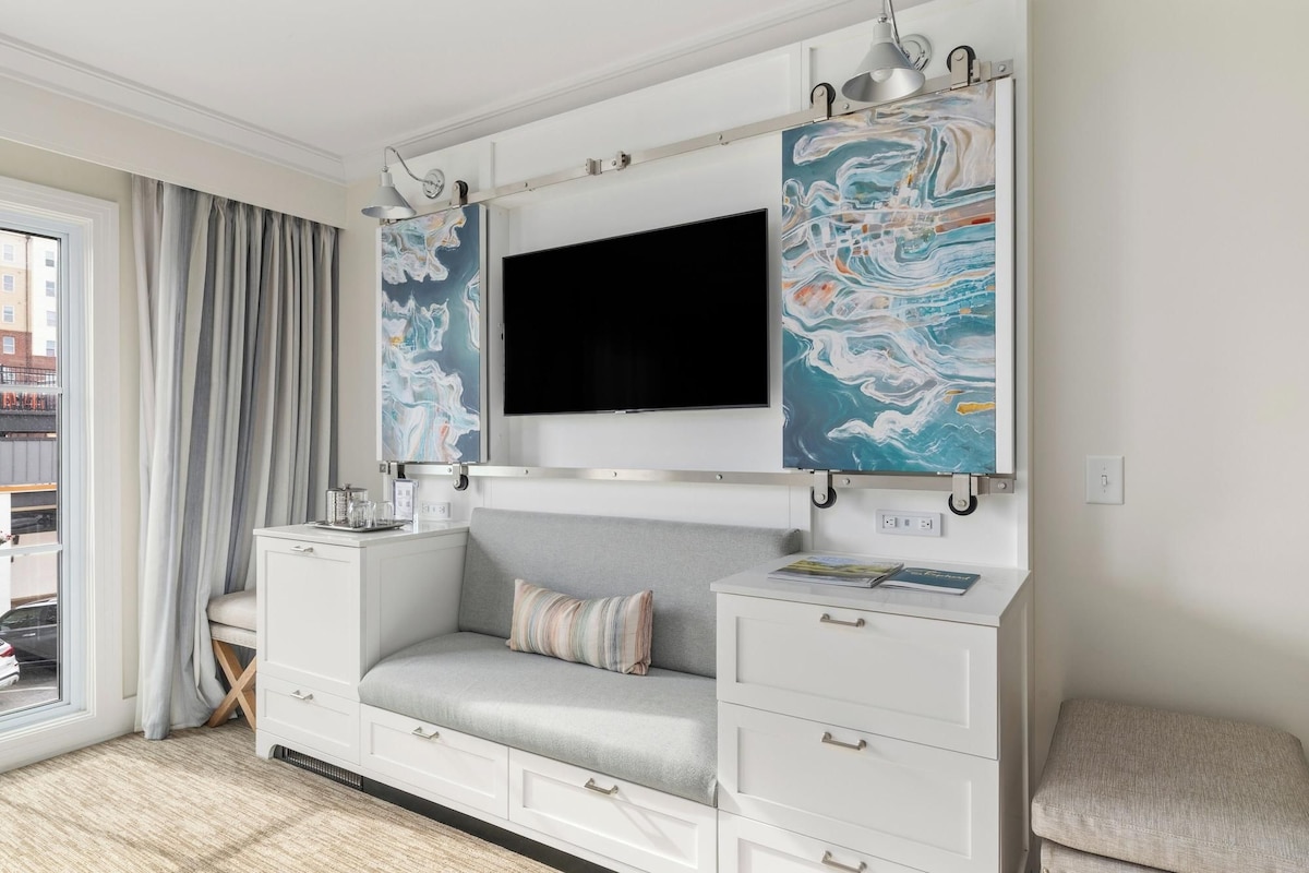 A modern living room with a sofa, a flat-screen TV, and abstract art on the walls.