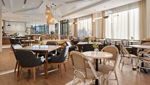 A spacious restaurant with high ceilings, wooden flooring, and a mix of modern and classic furniture.