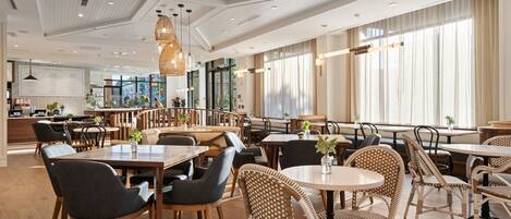 A spacious restaurant with high ceilings, wooden flooring, and a mix of modern and classic furniture.