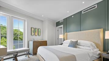 A modern hotel room with a large bed, a desk, and a bench by the window.