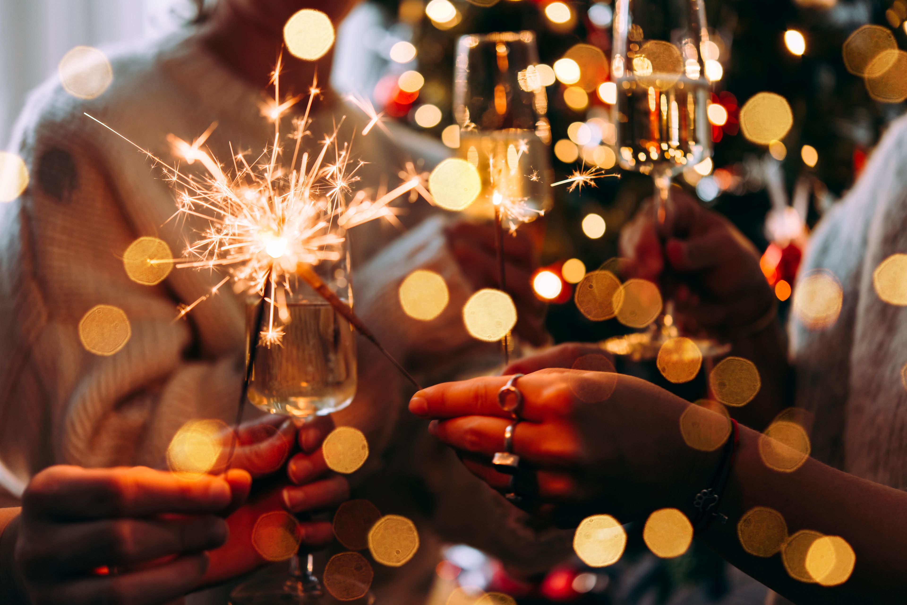 Hands holding glasses with sparklers, suggesting a festive or celebratory event.
