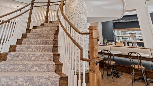 A multi-level interior with a spiral staircase, wooden railings, and a seating area with tables and chairs.