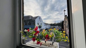 A window view of a building with a mural, a parking lot, and a flower bed.