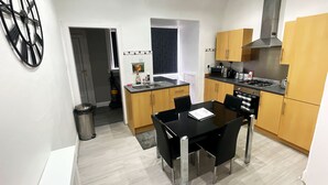 A modern kitchen with a dining table and chairs, wooden cabinets, a microwave, and a gas stove.