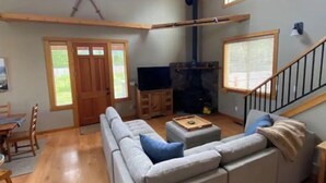 A living room with a sofa, a television, a fireplace, and a staircase. - Luxury Cabin in Recreation Paradise! Close to everything: Nature, Food, Suncadia (Cle Elum)
