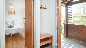 A bedroom with a bed, a wooden door, and a view of the outdoors. - 2 bedroom accommodation in Withleigh, near Tiverton (Withleigh, near Tiverton)