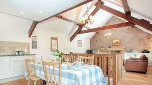 A dining area with a checkered tablecloth, wooden chairs, and a stone wall in the background. - 2 bedroom accommodation in Withleigh, near Tiverton (Withleigh, near Tiverton)