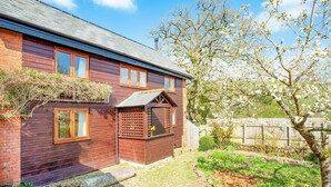 A wooden house with a brick section, a wooden fence, and a garden with a tree. - 2 bedroom accommodation in Withleigh, near Tiverton (Withleigh, near Tiverton)