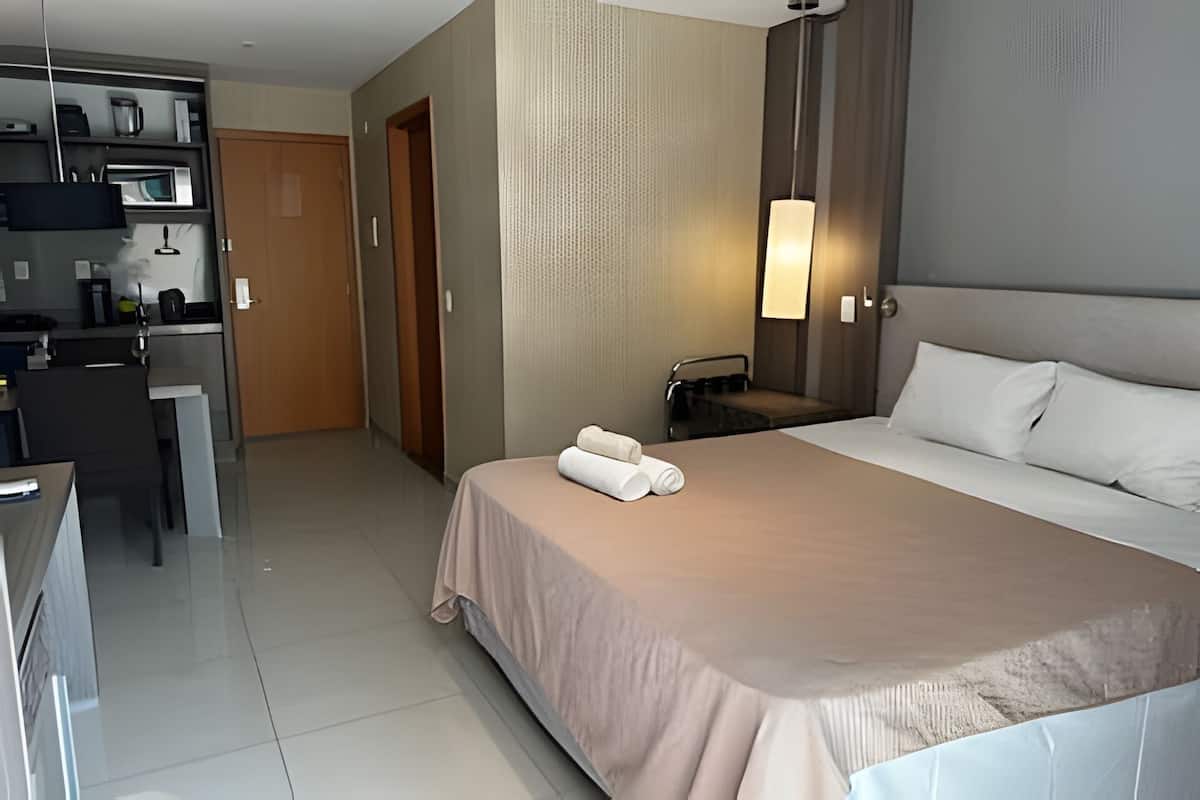 A hotel room with a bed, a desk, a chair, a wardrobe, and a bathroom.