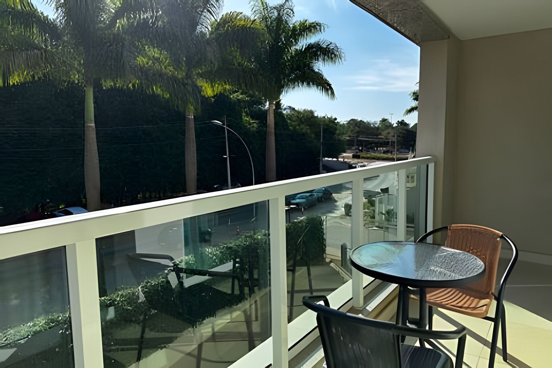 A balcony with a glass railing, a round table, and two chairs.