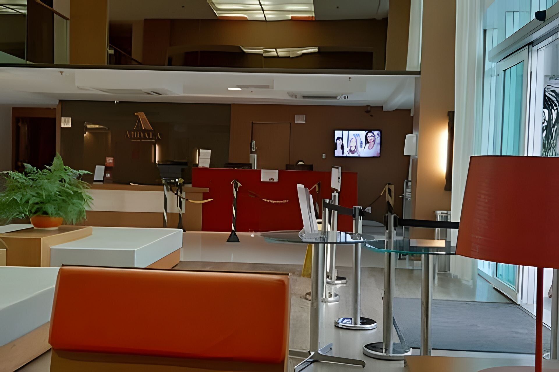 A reception area with a counter, a potted plant, and a television screen.