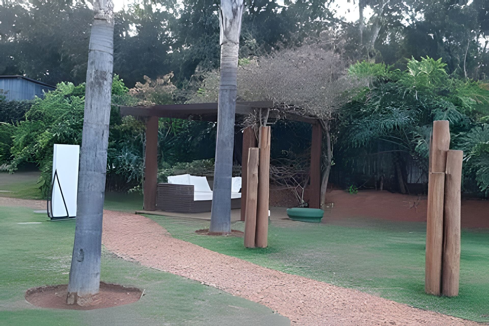 Un espace jardin agrémenté d’une pergola, d’une structure blanche et d’un banc vert.
