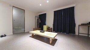 A spacious room with a wooden table, a small chair, a coat rack, and a desk with a computer. - BONATREE HOTEL (Busan)