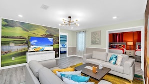 Een moderne woonkamer met een grote flatscreen televisie, een zithoek, een salontafel en een schilderij van een landschap.