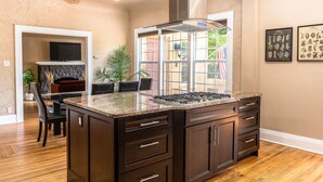 A spacious kitchen with dark wooden cabinets, a granite countertop, and a large island with a gas range. - 3/2 Luxury Spanish Villa - Pool - Pet Friendly (Lakeland)