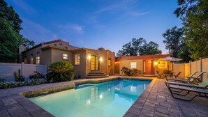 A swimming pool with a tiled deck, a covered patio area, and a small building with a red roof. - 3/2 Luxury Spanish Villa - Pool - Pet Friendly (Lakeland)