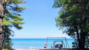 Una mesa de picnic y un columpio frente a una playa, con vista despejada al océano.
