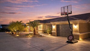 Una casa residencial con un aro de baloncesto, una entrada para coches y un garaje bien iluminado.