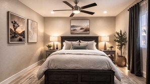 Un dormitorio con cama, dos mesitas de noche, ventilador de techo y decoración en la pared.