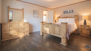 Un dormitorio con cama de madera, un aparador, un espejo y un letrero en la pared que dice 'RELAX'.