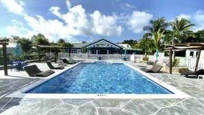 A rectangular swimming pool with a stone deck, surrounded by lounge chairs and a white fence. - This is a great vacation home with oceans views  (George Town)