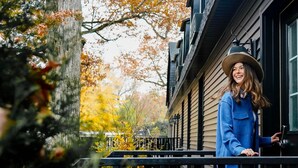 A person standing on a porch with a house in the background.