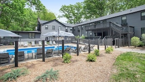 A modern building with a pool area, outdoor seating, and a staircase leading to an upper level.