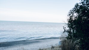 En strand med udsigt over havet, sandet og lidt vegetation.