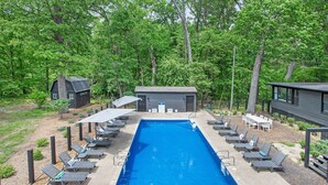 A rectangular pool with lounge chairs and tables around it, surrounded by trees and a small building. - The Neighborhood Hotel Grand Beach Suite 7 - Two Bedroom (Grand Beach)