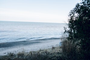 En strand med udsigt over havet, sandet og lidt vegetation.