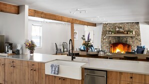 A modern kitchen with a stone fireplace, wooden cabinets, and a central island.