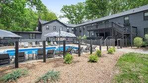 A modern building with a pool area, outdoor seating, and a staircase leading to an upper level.
