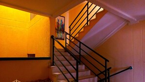 A staircase with black railings and a handrail, leading to a landing with a framed picture. - Hotel Nueva Esperanza (Barranquilla)