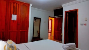 A hotel room with a bed, a mirror, and red doors. - Hotel Nueva Esperanza (Barranquilla)