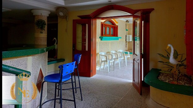 A room with a bar area, a dining area with chairs, and a view into another room. - Hotel Nueva Esperanza (Barranquilla)
