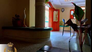 A lobby with a glass coffee table, a potted plant, and a decorative vase.