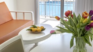 Ein modernes Hotelzimmer mit Balkon, einem weißen Tisch mit Zitronen und einem Strauß Tulpen.