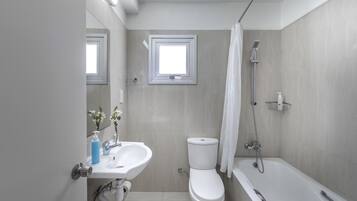 A modern bathroom with a toilet, sink, and bathtub.