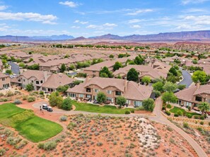 Zona residencial con varias casas, césped verde y un paisaje desértico al fondo.