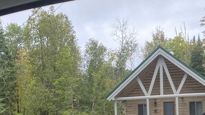 A cabin with a porch, a gravel driveway, and red chairs. - Log cabin~hike, hunt, ski,with direct snowmobile trail access and outdoor sauna. (Upton)