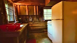 Eine rustikale Küche mit Holzausstattung, einem weißen Kühlschrank und einem roten Teppich.