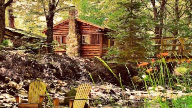 Een rustieke hut met een stenen schoorsteen, omringd door dicht bos en een kleine beek. Er staan twee houten Adirondack-stoelen bij het water.