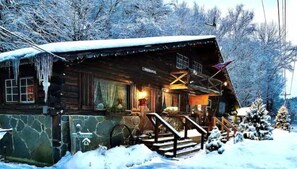 A log cabin with a stone foundation, a wooden porch, and a 'Welcome' sign. - Rustic Log Cabin #6 - "Fireside" (Lisbon)