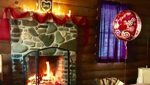 A cozy room with a stone fireplace, a couch, and a vase with red roses. - Rustic Log Cabin #6 - "Fireside" (Lisbon)