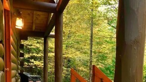 A wooden cabin with a covered porch, a dining table, and chairs. - Rustic Log Cabin #6 - "Fireside" (Lisbon)