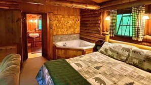 Une chambre aménagée dans un chalet en rondins, avec un grand lit, une baignoire et un plafond en bois.
