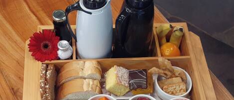 Una caja de madera con diversos alimentos y condimentos, como pan, queso, frutas y una cafetera.