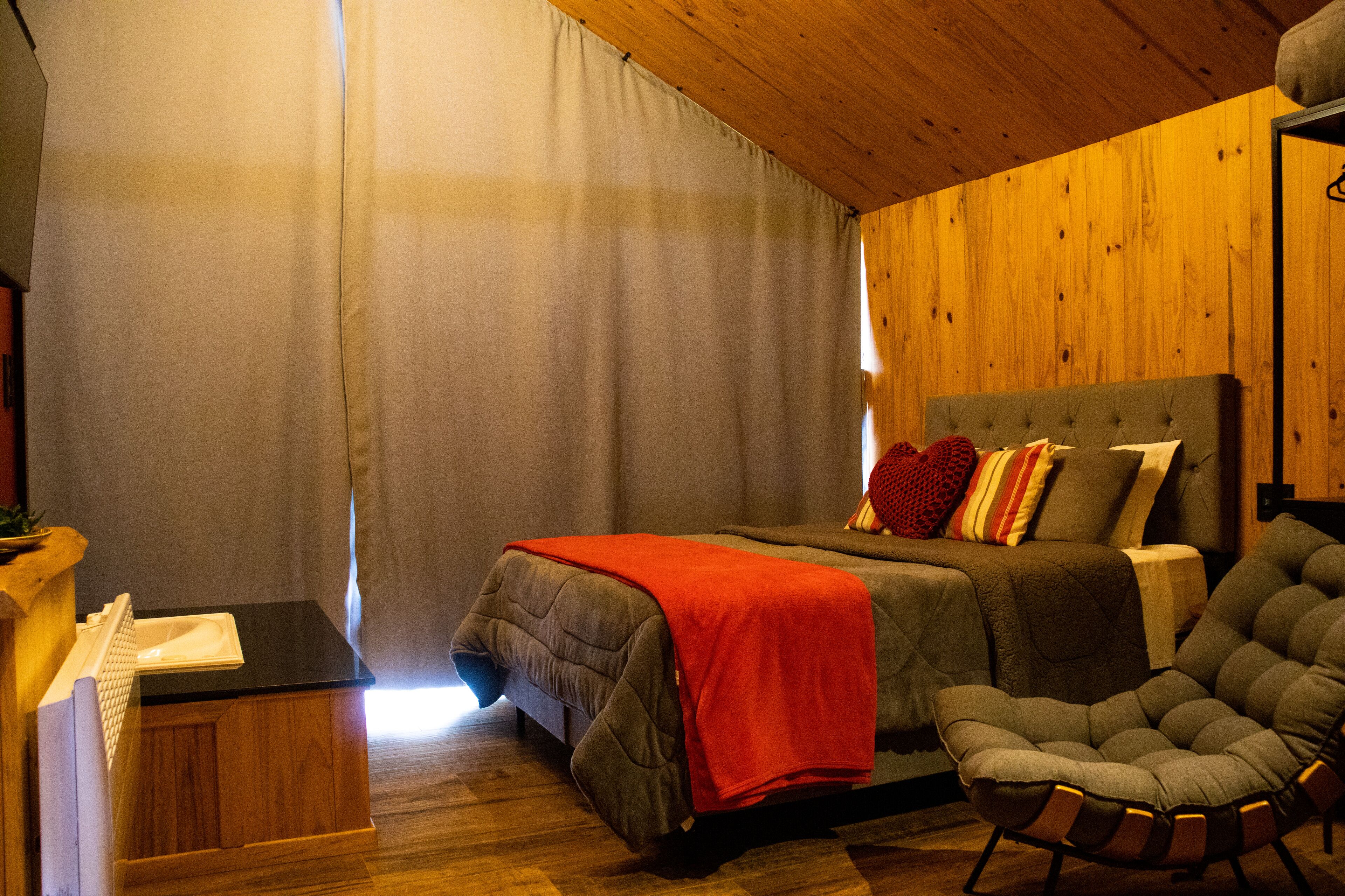 Une chambre à coucher avec un lit, une chaise, un bureau et une fenêtre avec des rideaux.
