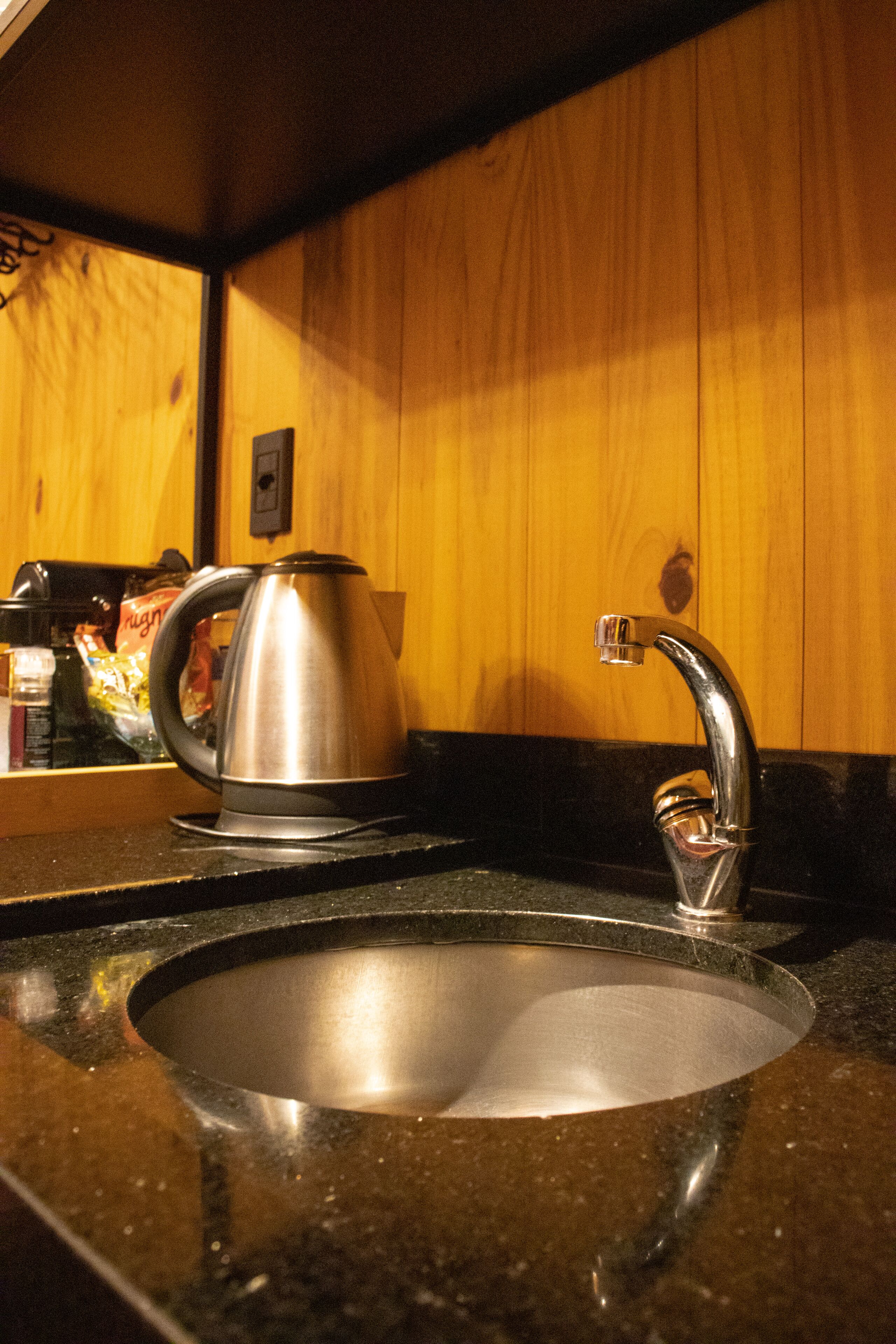 A kitchen sink with a stainless steel kettle and a modern faucet.