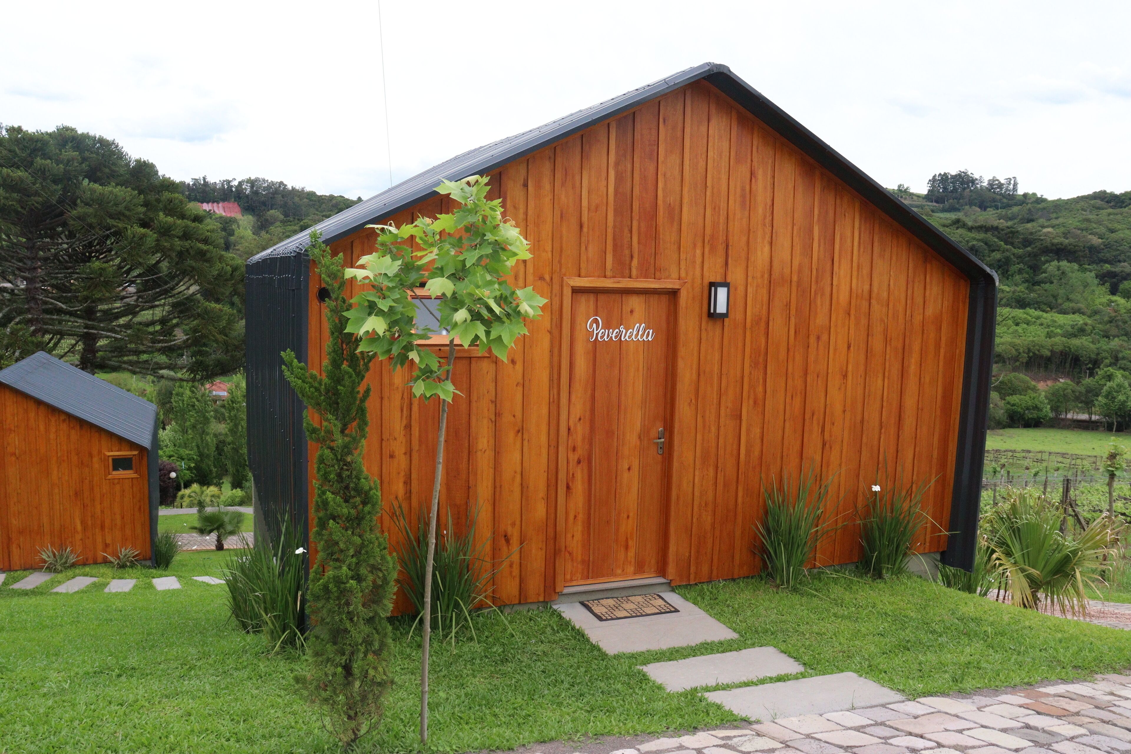 Une grange en bois avec une enseigne indiquant « Peverella » et une petite porte.